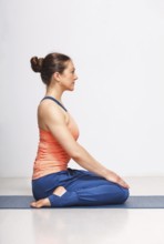 Woman in Hatha yoga asana Vajrasana, vajra pose or diamond pose on yoga mat on yoga mat in studio