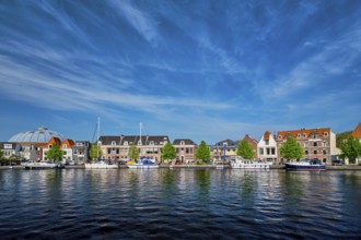 Boats and houses on Spaarne river with blue sky. Haarlem, Netherlands