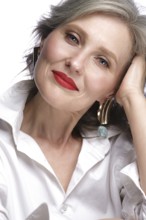 Portrait of a beautiful elderly woman in a white shirt with classic makeup and gray hair