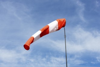 White-red windsock against blue sky, cloudy, wind vane, Germany, Europe