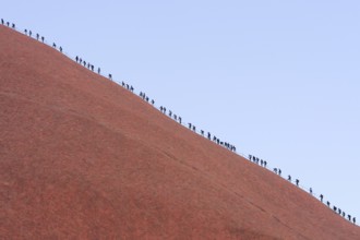 A long queue of people climbs the steep red rock face of Uluru (Ayers Rock), Australia, Oceania