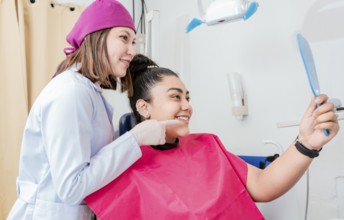 Female patient checking teeth after curing teeth in dental clinic. Dentist with satisfied patient