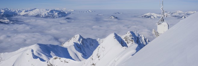 Mountain panorama in winter, snow-covered mountain peaks rise above cloud cover, view from