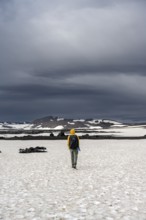 Hikers in snow-covered volcanic landscape with volcanic sand and petrified lava, crater of Askja