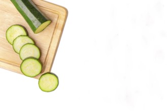 Courgettes (Cucurbita pepo), cut open, on wooden board, on white, copy room