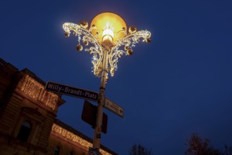 Christmas decorated street lamp on Willy-Brandt-Platz, behind it central station, Magdeburg,