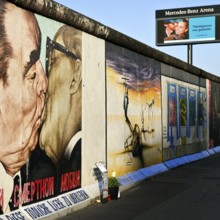 Brotherly Kiss, painting by Dmitri Vrubel on a remnant of the Berlin Wall with advertisements for