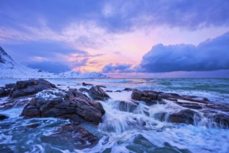 Waves of Norwegian sea on rocky coast in fjord on sunset with sun. Skagsanden beach, Lofoten