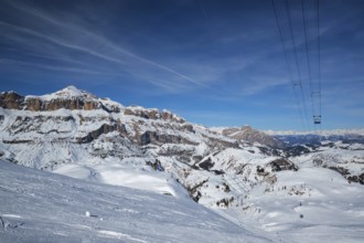 View of a ski resort piste with people skiing in Dolomites in Italy with cable car ski lift. Ski