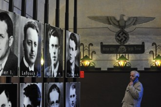 Visitors with audio guide looking at pictures of prisoners at Fort Breendonk, Belgium, Europe