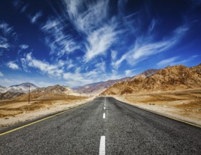 Travel forward concept background, road in mountains Himalayas with dramatic clouds on blue sky.