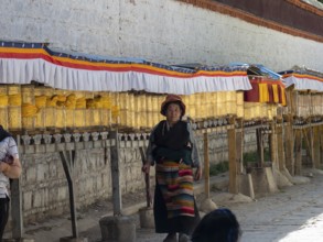 Pilgrims at golden prayer wheels, Xigaze, Tibet, China, Asia