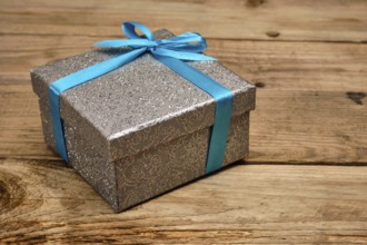 Gift birthday Christmas present concept, silver gift box with blue ribbon on old wooden background