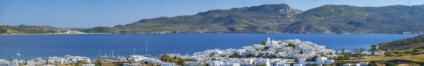 Panorama of Plaka village with traditional Greek church white painted Greek houses and ocean coast.