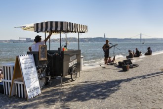 Lively terrace on the banks of the Tagus, drinks kiosk, backlit street musicians, Ribeira das Naus,