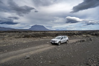 Car on a dirt road, Herðubreið Table Mountain behind, volcanic landscape, barren landscape,