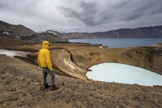 Tourist at the crater rim, crater lake Víti and Öskjuvatn in the crater of Askja volcano, volcanic