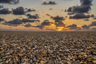 Empty pebble beach by the sea, sunset on the horizon