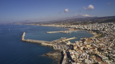 Drone shot, Venetian harbour, harbour wall, parts of the old town, mountains, lighthouse, blue sky,