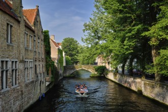 BRUGES, BELGIUM, MAY 28, 2018: Tourist boat with tourists in canal between old houses. Brugge