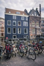 Bicycles in Amsterdam street near canal with old houses. Amsterdam, Netherlands