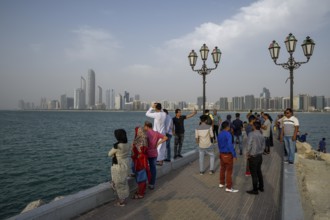 Locals in front of skyline at Wave Breaker Beach vantage point, Abu Dhabi, Abu Dhabi Emirate,