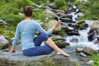 Yoga exercise outdoors, woman doing Ardha matsyendrasanaasana asana, half spinal twist pose at