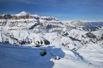 View of a ski resort piste with people skiing in Dolomites in Italy with cable car ski lift. Ski