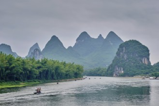 Tourist boats on Li river with dramatic karst mountain landscape in the background. Yangshuo,