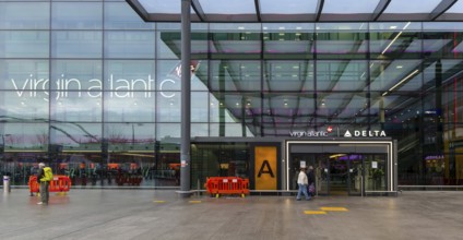 Passengers with luggage outside Virgin Atlantic, Terminal 3 building, London Heathrow Airport,