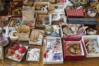 Earrings for sale displayed in boxes on table inside second hand goods and chattels store, Quebec,