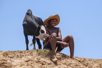 Smiling Malagasy boy posing with zebu calf, Belo sur Tsiribihina, Menabe Region, Central Highlands,