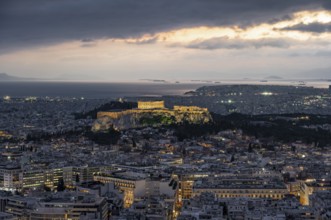 View over the sea of houses of Athens, illuminated Parthenon temple on the Acropolis, from Mount