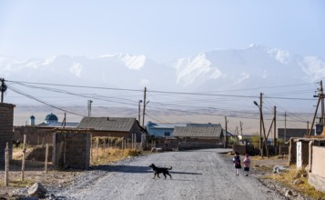 Schoolchildren and dog in the village of Sary Mogul, snow-capped mountains, Pamir Mountains, high