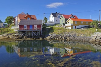 Different coloured hozhouses reflected in crystal clear sea water, Rorbuer, Henningsvaer, Lofoten,