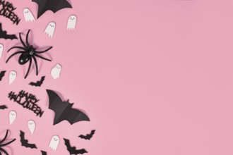 Halloween flat lay with bats, spiders, Happy Halloween text and cute ghosts on side of pink