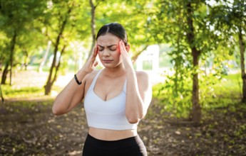 Runner woman with headache in a park. Athlete girl with migraine in a park. Young female runner