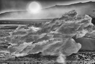 Backlit block of ice, b&w image, beach at glacier lagoon Jökulsarlon, Breiðamerkursandur, south