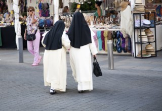 Two Roman catholic nuns linking arms crossing a road in Seville, Spain, Europe