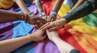 Diverse people hands over rainbow LGBTQ flag showing love, affection and unity, AI generated