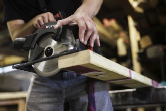 A man cuts wood with a hand-held circular saw. Berlin, 14.08.2024