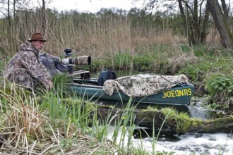 A canoe with camouflaged camera in a swamp, surrounded by vegetation and quiet nature, boat of a