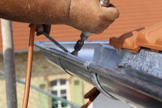 Roofer doing tinsmith work on a gutter