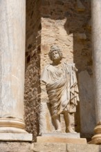 Stone statue in front of ancient columns and stone walls, a detail of Roman architecture and