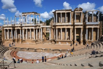 Ancient Roman theatre with stone ruins in the open air, occupied by a few visitors, Teatro Romano