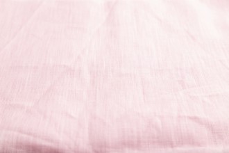 Fragment of smooth pink linen tissue. Side view, natural textile background and texture