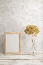 White wooden frame mockup with dried hydrangea in glass on gray concrete background. Blank,