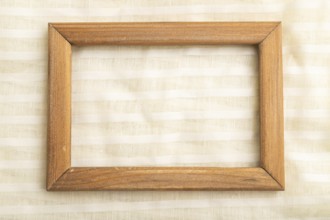 Wooden frame on smooth white linen tissue. Top view, flat lay, natural textile background and