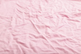 Fragment of pink cotton tissue. Side view, natural textile background and texture