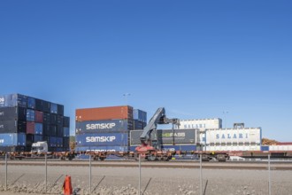 Loading of freight containers with a crane on railway wagon at an industrial area